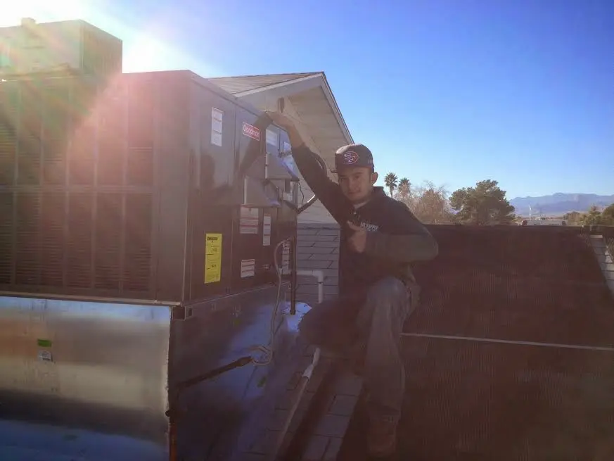 HVAC technician performing HVAC Inspection on a rooftop unit in Grove